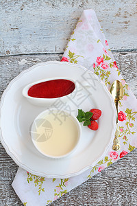 以浪漫的风格在锅里加草莓酱的甜点肉饼空气碟子布丁奶油红色白色绿色木头服务花朵图片