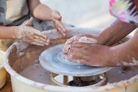 土陶制作年轻陶匠的手 在圆圈上创造了一个土罐陶瓷工匠压力陶器艺术家男生制品车轮手工业花瓶背景