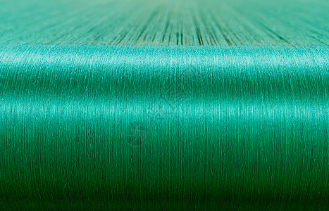 一家纺织厂织物机的折叠圈上的绿丝绸纺织品工厂布料牙线棉线织物翘曲控制背景纺织图片