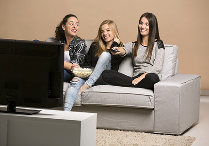 女孩看电影乐趣爆米花展示观众青少年幸福手表沙发团体家庭图片