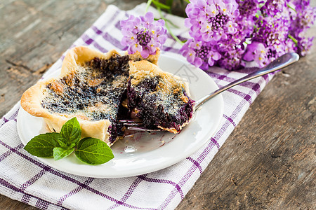 盘子和紫花上的蓝莓塔板叶子烘烤馅饼美食餐巾摄影桌子浆果水果奶油图片