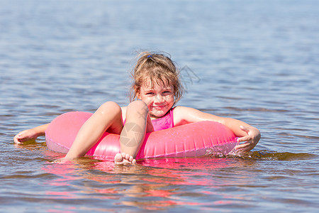 5岁女孩在河里游泳 坐在大腿游泳上 快乐地看着框架图片