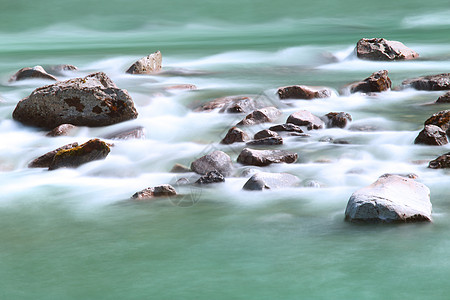 江流和石头白色绿色运动力量蓝色急流旅行溪流风景速度图片