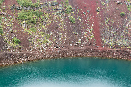 Kerid是一片绿绿石颜色的火山口湖 冰岛红色绿色天空蓝色火山口圆形地标陨石火山风景图片