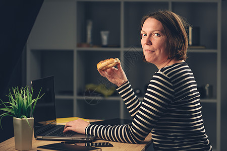 女人在办公室里吃芝麻百吉饼图片