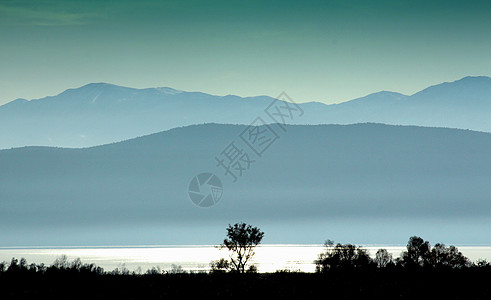 在马西多尼亚湖边的白日落太阳光线薄雾金子海滩反射金色游客晴天图片
