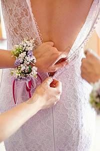 女伴娘在婚礼的清晨帮助新娘穿衣服图片