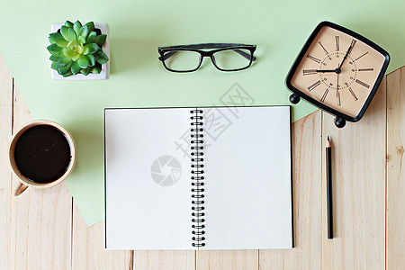 最顶端的工作桌视图 空白笔记本 铅笔 咖啡杯 眼镜 回响闹钟和木制背景的装置图片