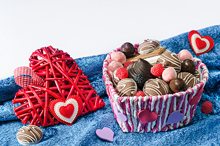 糖果篮子 饼干和装饰情人节的心 在蓝色天鹅绒布白色背景图片
