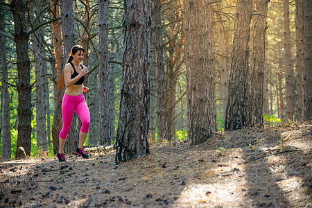 年轻女子在美丽的野生松树林的轨迹上奔跑 活跃的生活方式概念 文字空间运动员活动农村女性运动跑步公园训练慢跑卫生图片