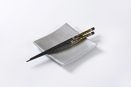 空平板上的黑筷子黑色用具花卉寿司盘装饰图案餐具美食方盘盘子背景图片