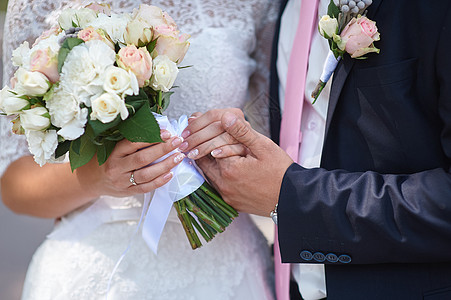 新郎握着新娘的手和结婚花束图片