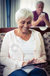 使用数字石板的老年妇女家庭退休电脑滚动闲暇女性电话头发快乐技术图片