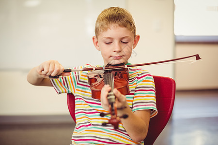 小提琴课在课堂上玩小提琴的男生童年爱好椅子服装专注闲暇学校学习知识班级背景
