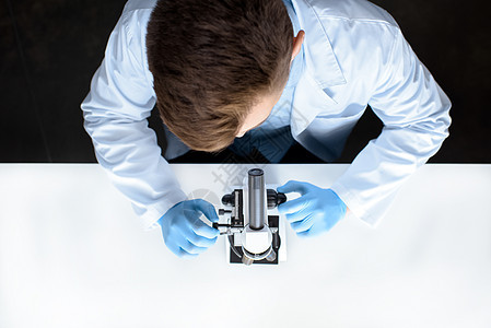 科学家与实验室显微镜一起工作的顶部视图工作服分析手套化学品职业防护男人乳胶成人科学图片