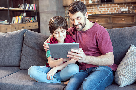 父亲和儿子在家中使用数字平板电脑微笑图片