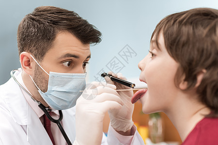 以医疗面罩检查小男孩喉咙的令人惊讶的医生图片