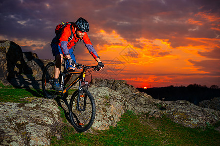 赛车手在美丽的日落山边骑着 极具活力的运动和冒险概念 的自行车下春落雪山下坡头盔男性成人行动骑士天空爬坡运动员乐趣图片
