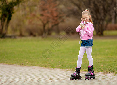 直排轮小斯卡特轮滑耳机孩子活动旱冰享受公园休闲微笑手机背景