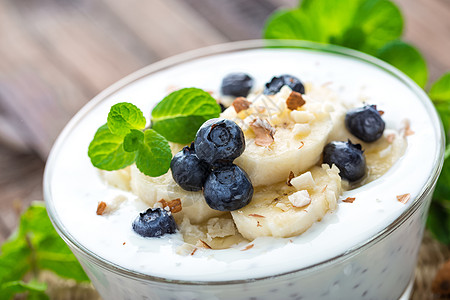 配有新鲜蓝莓 香蕉和杏仁果的酸奶 甜甜点用于健康早餐坚果奶油玻璃甜点水果食物浆果勺子营养奶制品图片