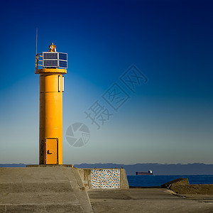 断水堤坝上的黄灯塔正方形建筑蓝色海浪石头橙子海景天空巨石收音机图片