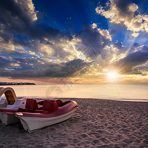 日落时有船只的平静海滨沙滩图片
