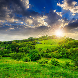 日落时山中草原附近的森林旅游耀斑季节绿色太阳环境射线光束天空阳光图片