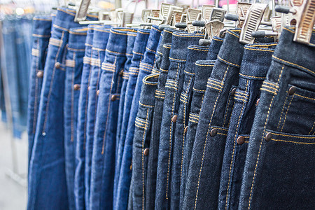 很多不同的蓝色牛仔裤衣架服装销售展示织物架子市场陈列室店铺零售图片