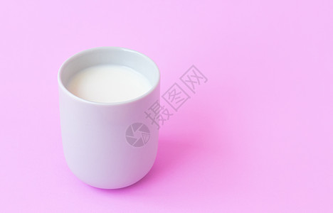 粉红色背景的白陶瓷杯中的牛奶 选择性焦点高清图片