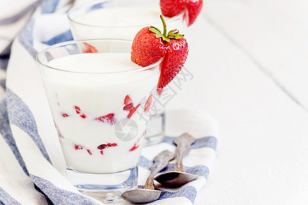 甜甜酸奶和草莓层 在蓝色条纹的玻璃杯中食物牛奶奶制品饮食健康奶油毛巾水果桌子早餐图片