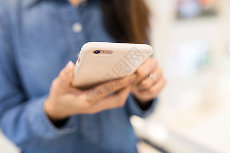 手机理财女性使用移动电话的情况手机女孩手指购物细胞购物中心车站牛仔裤蓝色短信背景