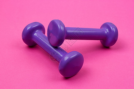 粉红色背景的紫色哑铃重量运动女性保健卫生肌肉力量粉色举重杠铃图片
