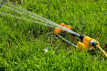 黄色草坪喷洒灭水器在绿色g上铺满水的近镜头图片