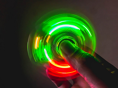 手旋转的浅彩色卷饼辉光滚筒乐趣游戏塑料活力运动压力工具手指背景图片