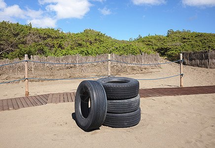 四胎轮胎丢弃在海滩上环境问题垃圾晴天生态橡皮黑色人行道栅栏图片