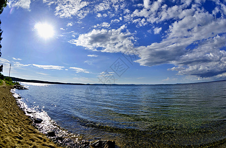 明亮的蓝天空 湖岸上有白云日落森林地平线太阳树木季节阳光木头海岸线蓝色图片