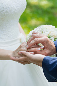 新郎把戒指放在新娘的手上 照片特写珠宝推杆花朵男人丈夫胸花配偶教会金子幸福图片