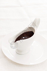 在白瓷沙酱船上的巧克力酱 白色背面牛奶营养饮料食物小吃蛋糕可可香料豆子糖浆图片