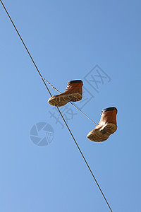 在清蓝的天空上挂在一条线上的靴子棕色电话街道金属蓝色绳索电缆乐趣鞋类青年图片
