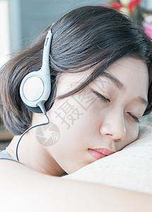 年轻的亚洲女性短发听音音乐枕头技术房间女孩寒意歌曲青少年耳机电话收音机背景图片