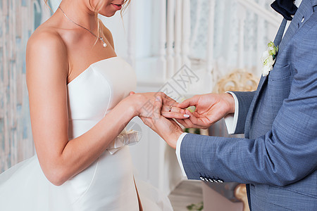 新郎把戒指放在新娘的手上 照片特写女性幸福教会手指交换裙子推杆珠宝仪式丈夫图片