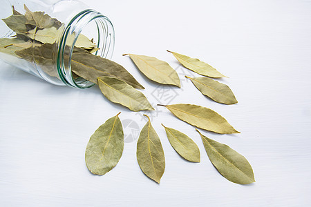 白色木质背景的玻璃罐里干枯的海湾叶子优胜者味道树叶文化花园草药营养植物花圈香料图片