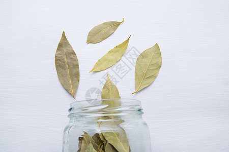 白色木质背景的玻璃罐里干枯的海湾叶子味道花园草药文化蔬菜食物优胜者桂冠植物草本图片