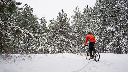 在美丽的冬季森林的红色骑马山自行车中 极端运动和概念车轮娱乐蓝色锻炼骑士男人速度踪迹天空头盔图片
