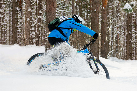 在美丽的冬季森林中的山上骑车的蓝色漂泊赛事中 极具体育和概念木头速度娱乐山地车耐力赛踪迹活动自行车漂移头盔背景图片