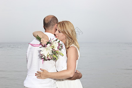 海滩上的年轻夫妇花束男性婚礼夫妻女士男人浪漫背景图片