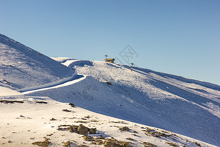 山顶阳光明媚的一天晴天白色爬坡胜地中心天空蓝色滑雪板滑雪高度背景图片