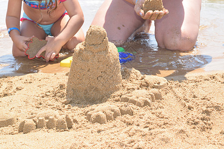 在海滩上建沙滩城堡支撑热带海岸线孩子们建筑妈妈乐趣阳光闲暇沙堡图片