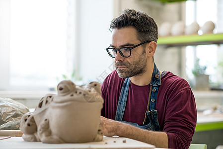 在明亮的陶瓷工作坊里 穿着来自Raw Clay的Apron雕塑肖像雕刻男性工艺手工业陶器制品雕像青蛙创造力用具图片