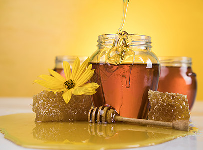 蜂蜜和木棍子放在桌子上梳子金子蜂巢花蜜治愈液体乡村国家疗效石匠背景图片